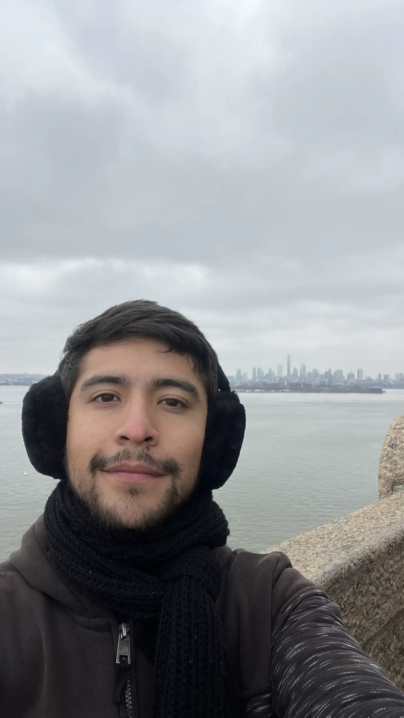 Cesar Cruz by the water with a city skyline behind
