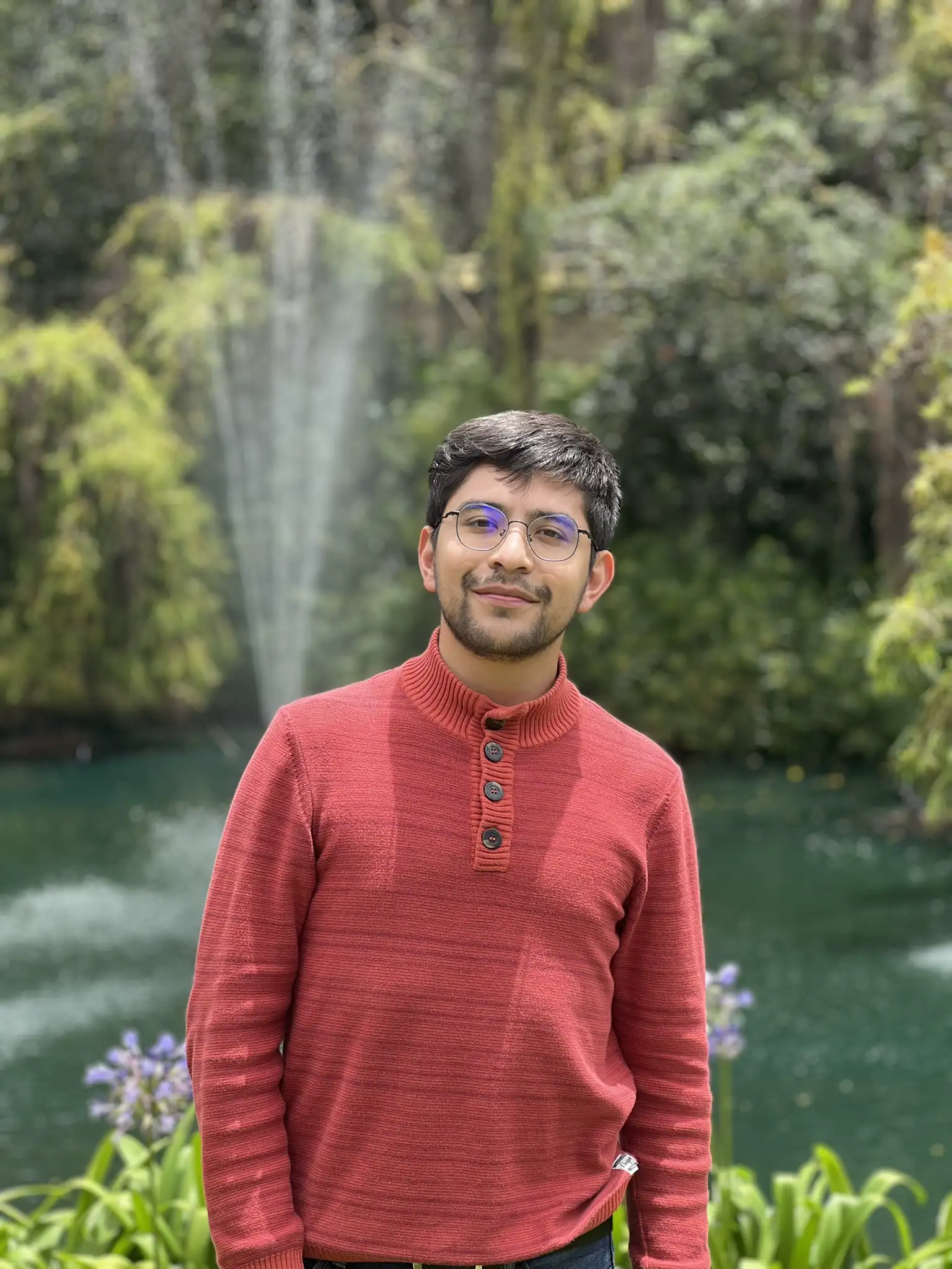 Cesar Cruz in a red sweater by a fountain